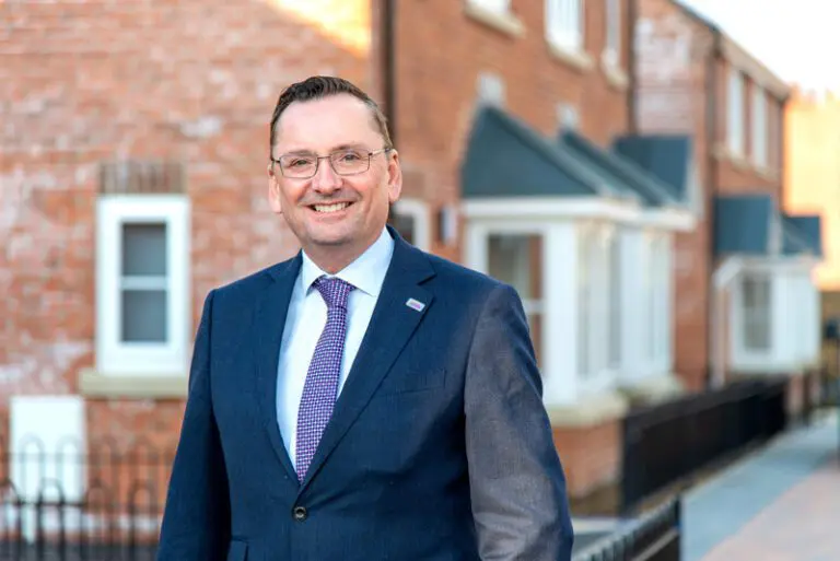 Andy Wallhead in a suit outside homes