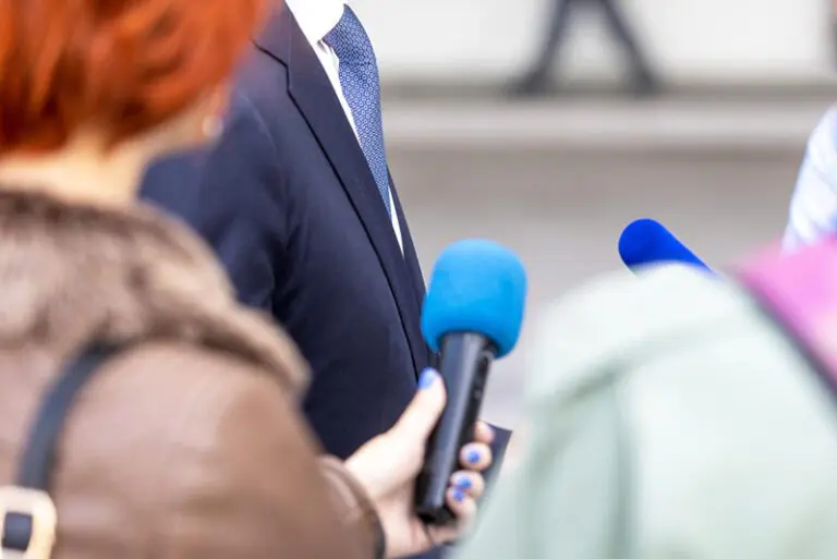 holding mics in front of a man in suit