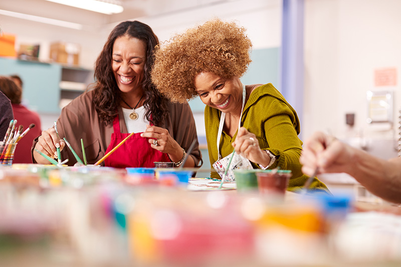 two women smiling while doing painting