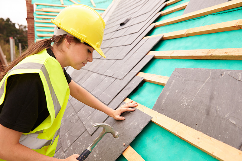 woman in hardhat fixing a roof