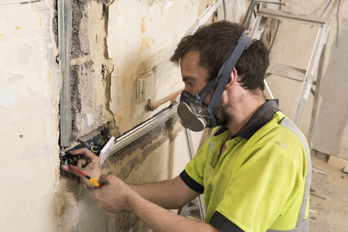 a man with a mask performing an electrical repair